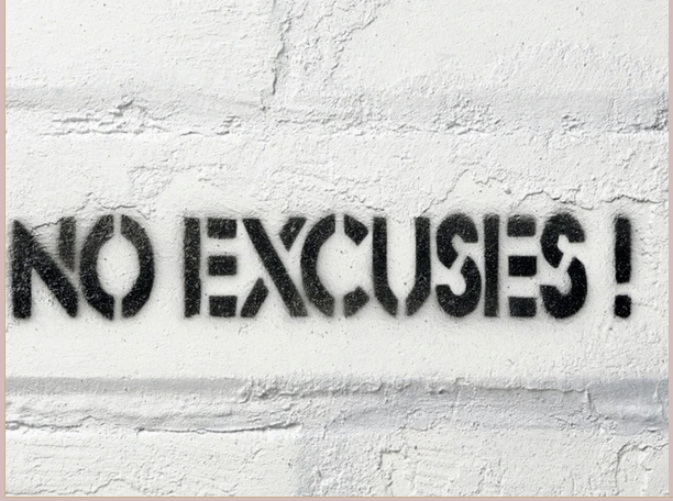 A white wall with the words no excuses written in black.